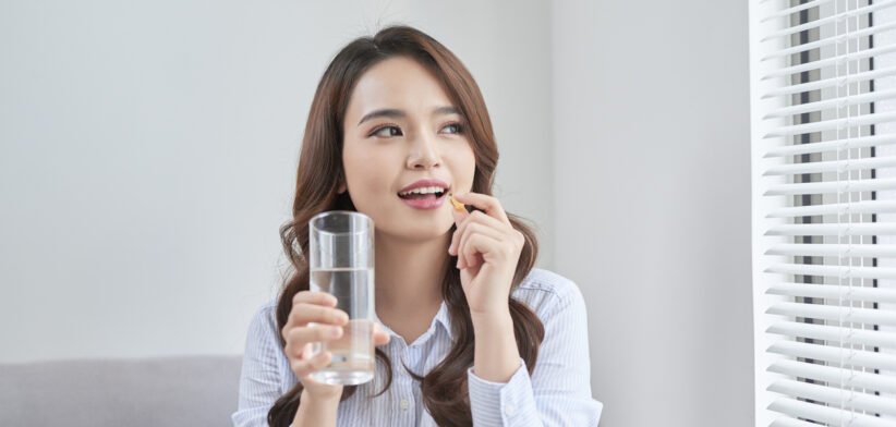 Beautiful Smiling Woman Taking Vitamin Pill. Dietary Supplement