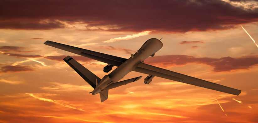 military UAV airplane flies against backdrop of beautiful view of the sunset sky orange with clouds and condensa