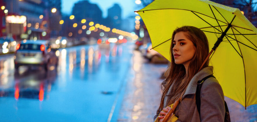 Woman holding a yellow umbrella while waiting for a cab