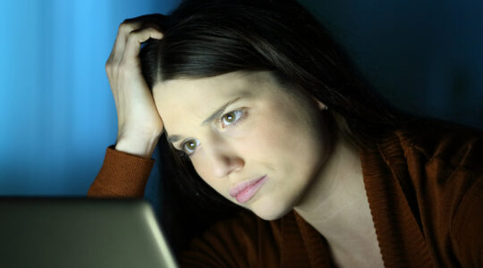 Worried woman in the night checks laptop