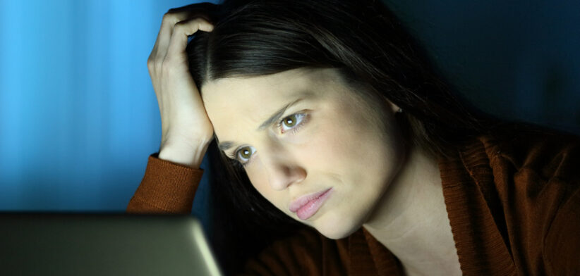 Worried woman in the night checks laptop