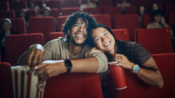 Happy diverse couple enjoying in a movie at cinema.