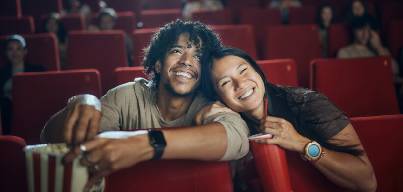 Happy diverse couple enjoying in a movie at cinema.