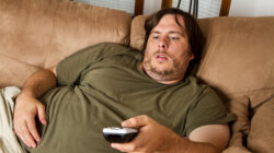 Overweight man watching TV on the couch
