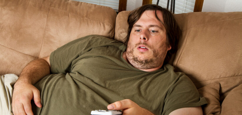 Overweight man watching TV on the couch