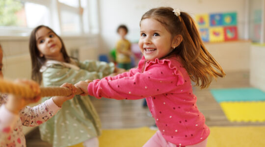 Children playing a game of tug of war in playroom