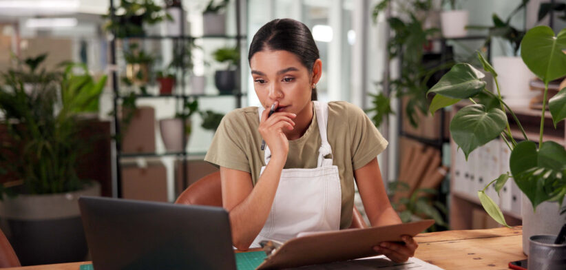 Woman, florist and clipboard with laptop at shop with stress, thinking and problem solving at small business. Person, pc and sustainability for plants with mistake, crisis and lost order on web store