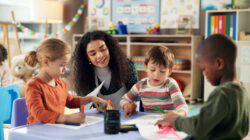 Drawing, education and teacher with children in classroom for learning, students and creative art. Growth, kindergarten and academy with woman and kids at school for helping and child development
