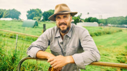 Australian farmer smiling at the ranch leaning on a fence