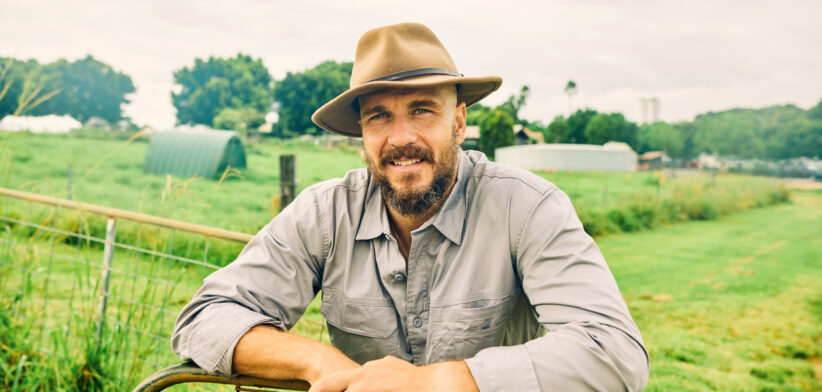 Australian farmer smiling at the ranch leaning on a fence