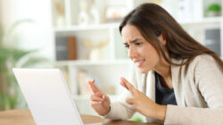 Hopeful woman crossing fingers checking laptop waiting for result