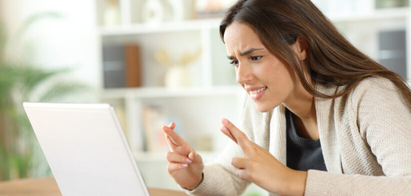Hopeful woman crossing fingers checking laptop waiting for result