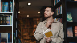 Happy Adult Man Reading a Yellow Book in a Cozy Library, Smiling Casual Moment
