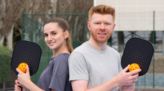 Young couple enjoying outdoor pickleball game at court