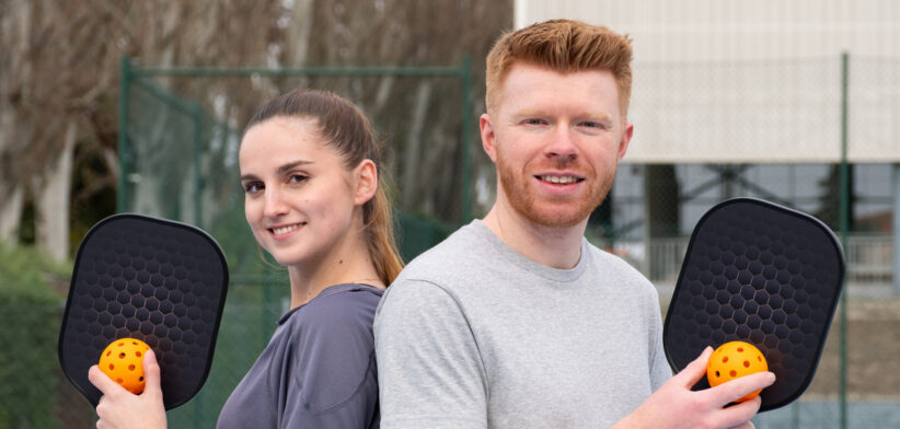 Young couple enjoying outdoor pickleball game at court