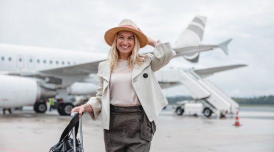 Smiling Female Tourist In Front Of A Plane