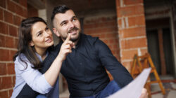 Happy couple analyzing housing project at construction site