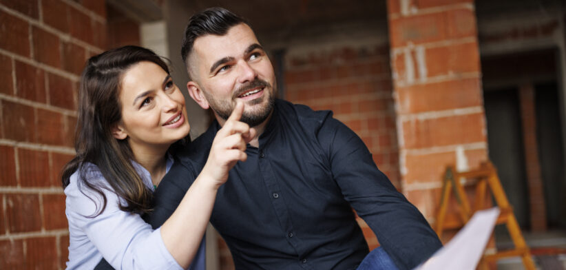 Happy couple analyzing housing project at construction site