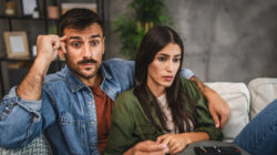 upset adult couple watch scary movie on television