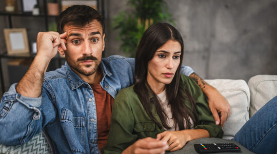 upset adult couple watch scary movie on television