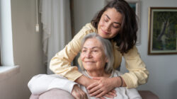 Daughter Hugging Senior Mother From Behind Holding Hands