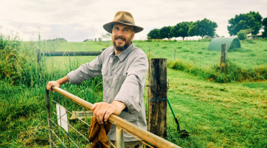 Australian farmer smiling at the ranch leaning on a fence