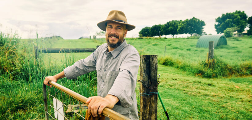 Australian farmer smiling at the ranch leaning on a fence