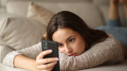 Woman checking phone lying on a couch in a house