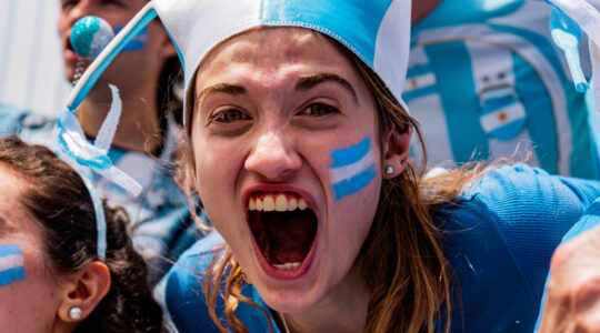 Portrait of a passionate female fan celebrating during an Argentine football match in the stands