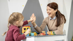 Preschool teacher and child high fiving during playtime