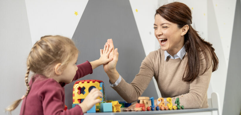 Preschool teacher and child high fiving during playtime
