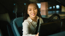 Woman driving modern electric car interacting with touchscreen