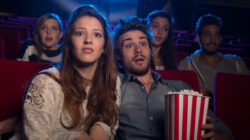 Young couple at the cinema watching an horror movie