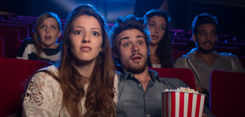 Young couple at the cinema watching an horror movie