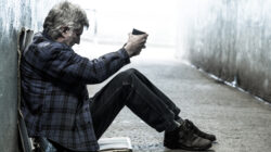 Homeless senior adult man sitting and begging in subway tunnel