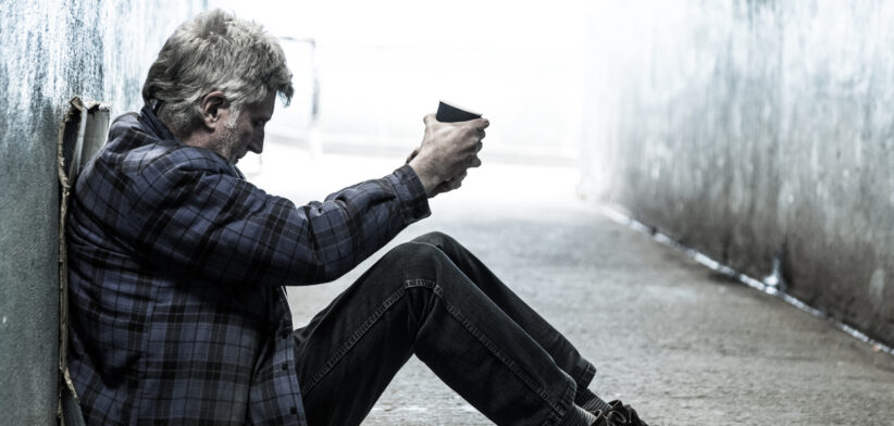 Homeless senior adult man sitting and begging in subway tunnel