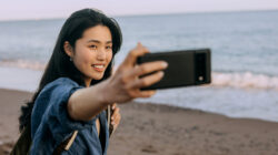 Chinese woman takes selfie on a sunny beach in Spain with beautiful sea and sand in background