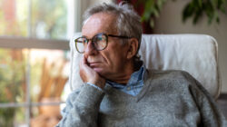 Senior man looking out of window at home
