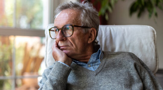 Senior man looking out of window at home