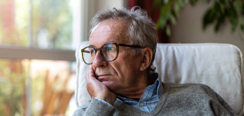 Senior man looking out of window at home
