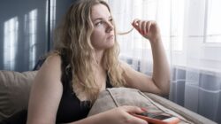 Sad young woman using mobile phone on sofa