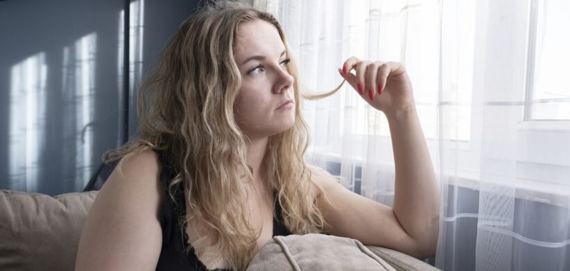 Sad young woman using mobile phone on sofa