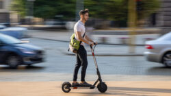 Young man bypassing traffic with e-scooter