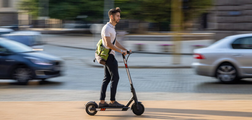 Young man bypassing traffic with e-scooter