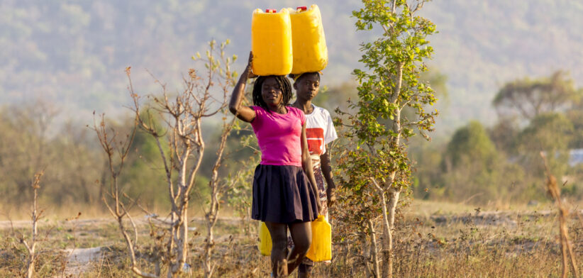 Two girls carrying gallons of Water