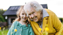 Granddaughter spending time with elderly grandma, picking wildflowers. Senior lady spending time in nature.