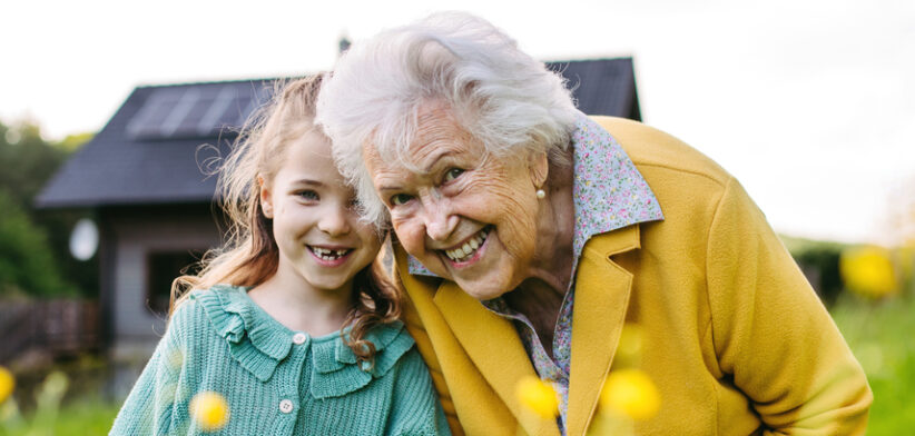 Granddaughter spending time with elderly grandma, picking wildflowers. Senior lady spending time in nature.
