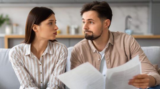Worried couple reviewing documents with laptop