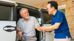 Caregiver helping senior man get in the car.