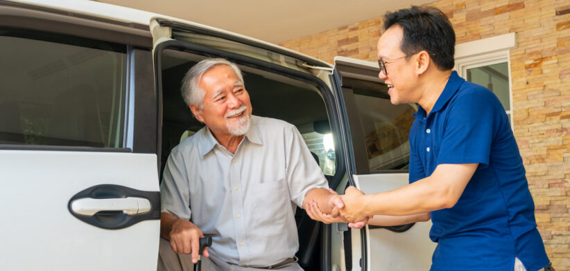 Caregiver helping senior man get in the car.